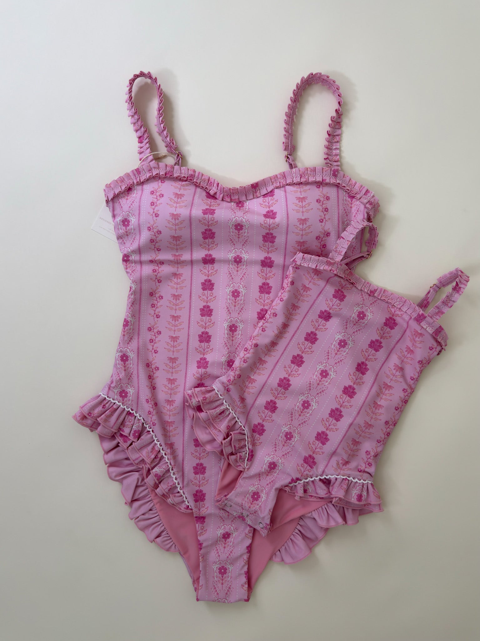 Pink  swimsuit with floral pattern on a light gray background